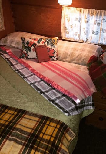 Bed in 1957 RV with books, coffee cups and blankets