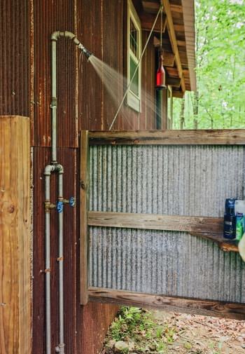 Outdoor shower under the eave surrounded by metal and wood walls