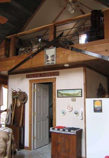 Interior of cabin with fishing and outdoor decor, vaulted ceiling, and a loft with ceiling fan.