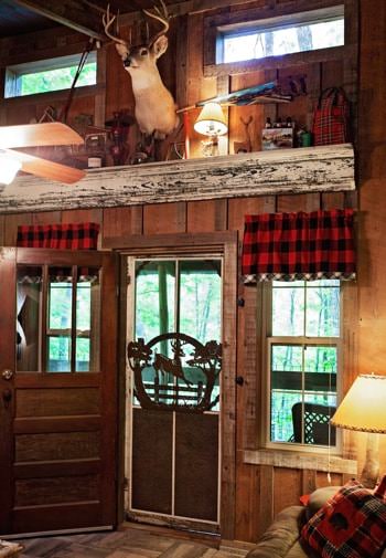 Cabin interior with tall ceilings, windows, and deer head mounted on the wall