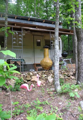 Exterior of cabin with a chiminea and charcoal grill surrounded by trees