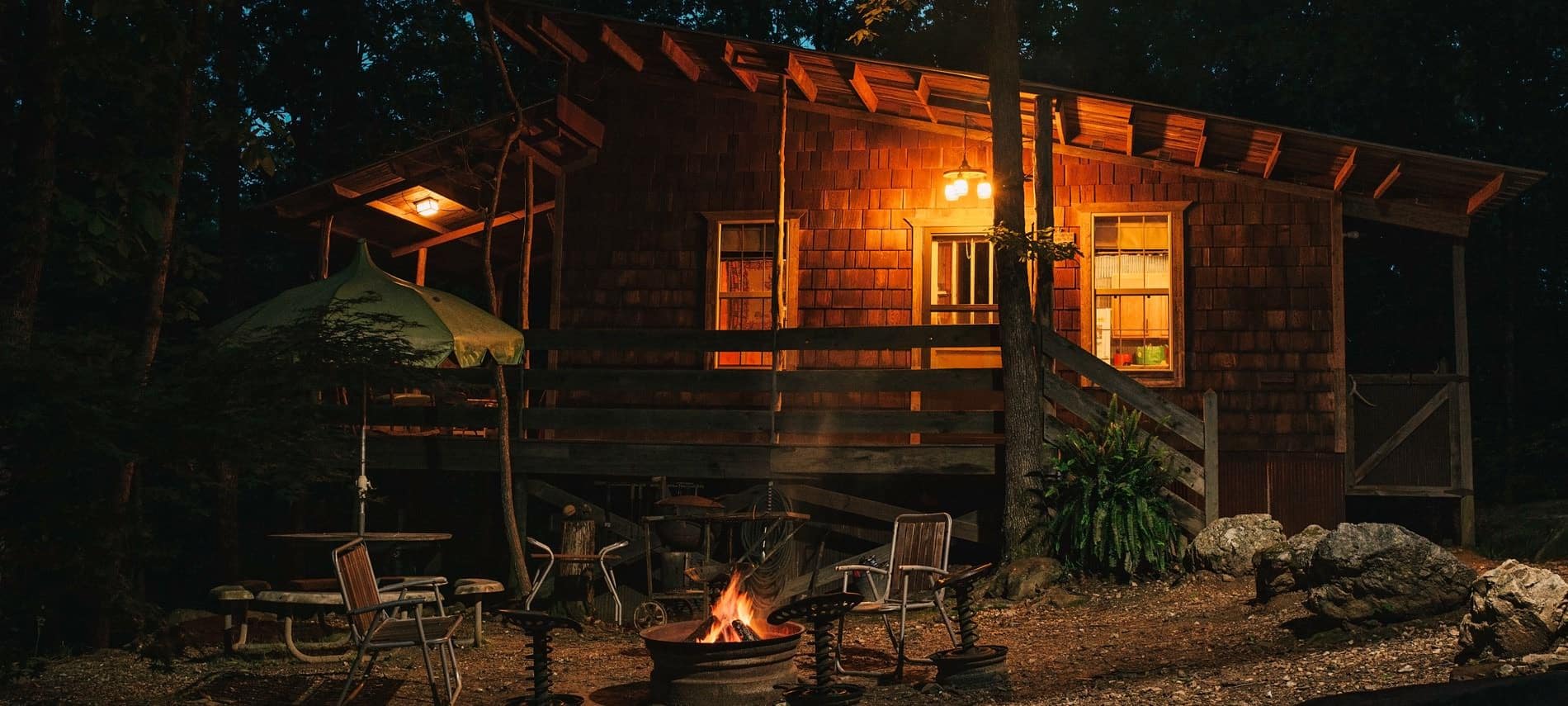 Exterior view of cabin at night with warm glowing fire pit